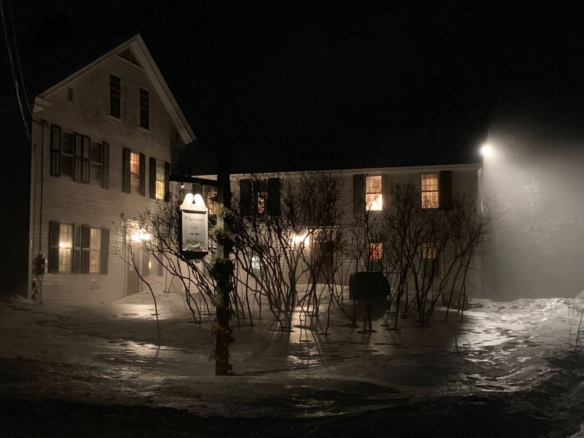 The inn on a winter night, windows and sign lit